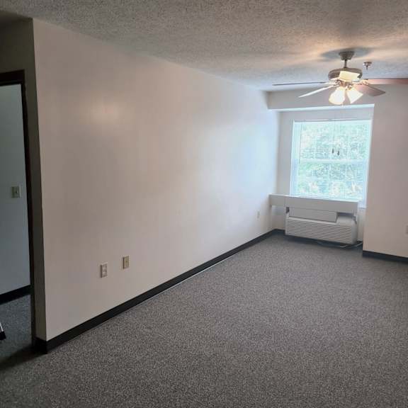 an empty room with a ceiling fan and a window