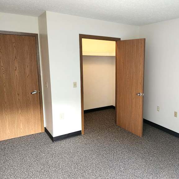 an empty room with two doors and a closet