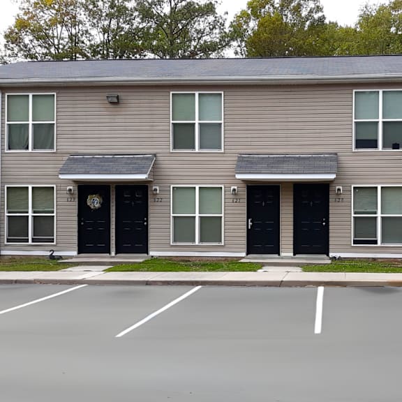 an apartment building with black doors and a parking lot