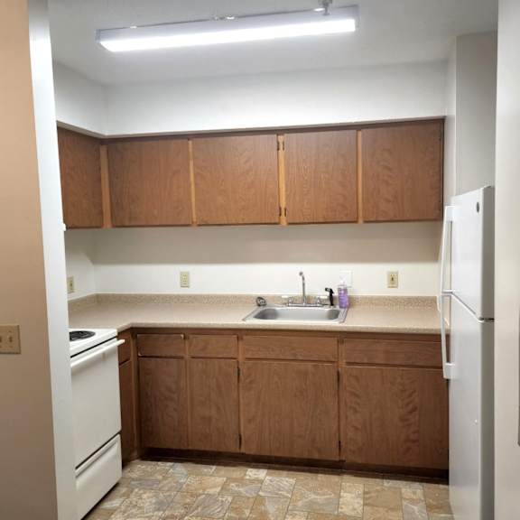 an empty kitchen with white appliances and wooden cabinets