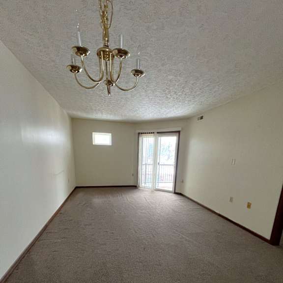 a room with a chandelier and a window with a view of a building outside.