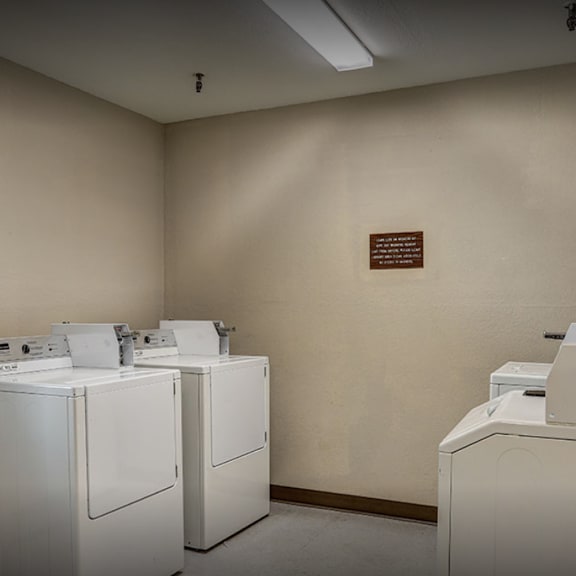 a laundry room with four washers and dryers and a door to a door