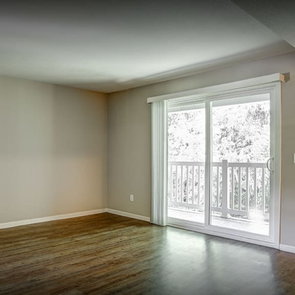 an empty living room with wood floors and a door to a balcony