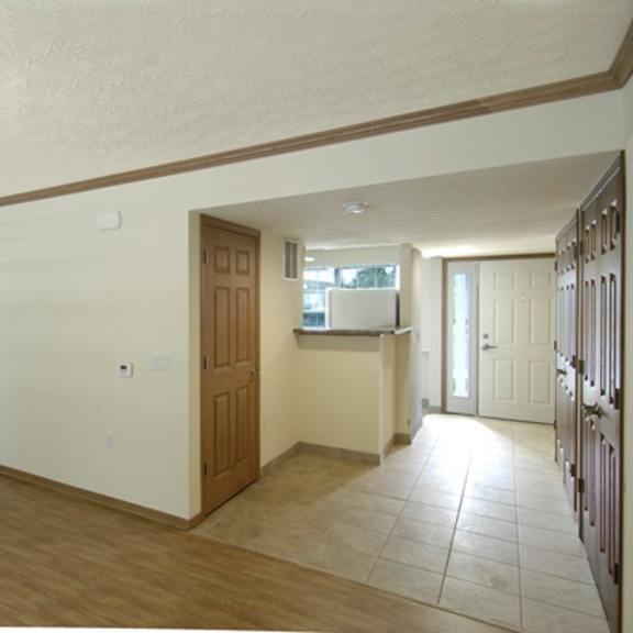 an empty living room and kitchen with a wooden door