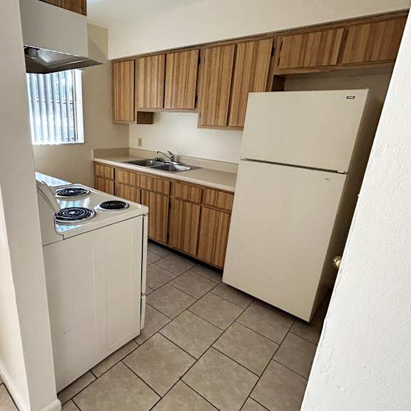 a white refrigerator is in a kitchen with wooden cabinets.
