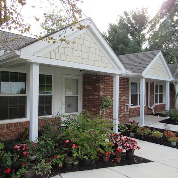 a front porch with flowers in front of a brick house