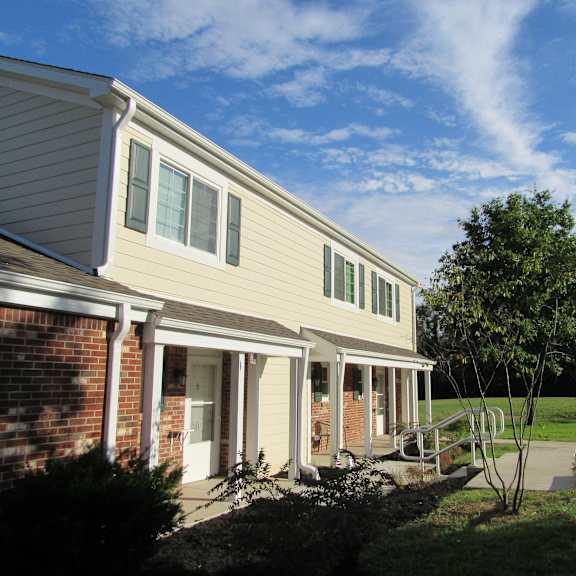 a view of the side of a house with a porch and a tree