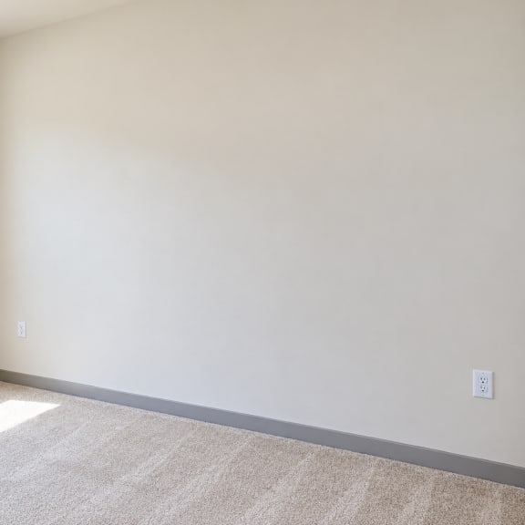 a room with a carpeted floor and a window with blinds.