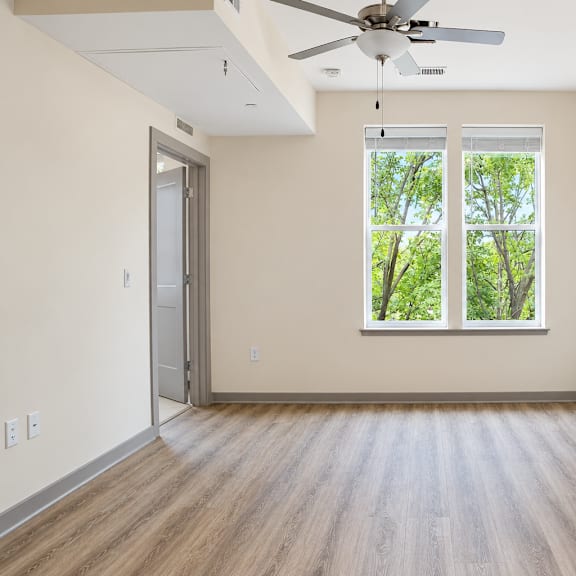 a room with a ceiling fan and a window overlooking trees.