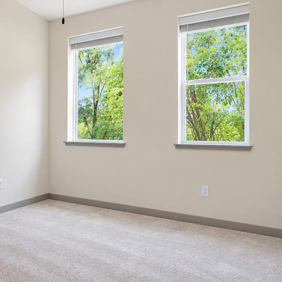 a room with two windows showing trees outside.