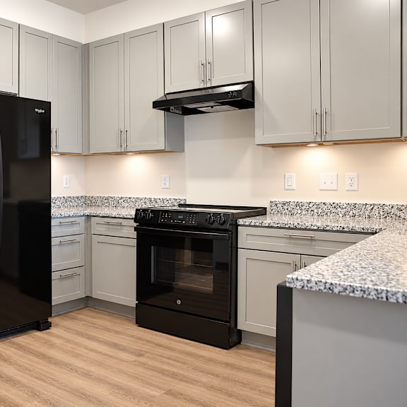 a black refrigerator stands in a kitchen with a black oven.