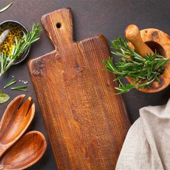 a wooden cutting board is surrounded by various spices and herbs.
