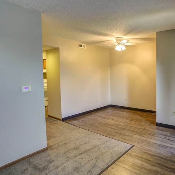the living room and dining room of an empty house with a ceiling fan