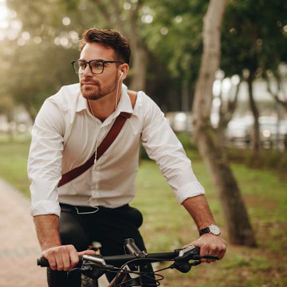 a man in a white shirt and suspenders is riding a bicycle on a path.