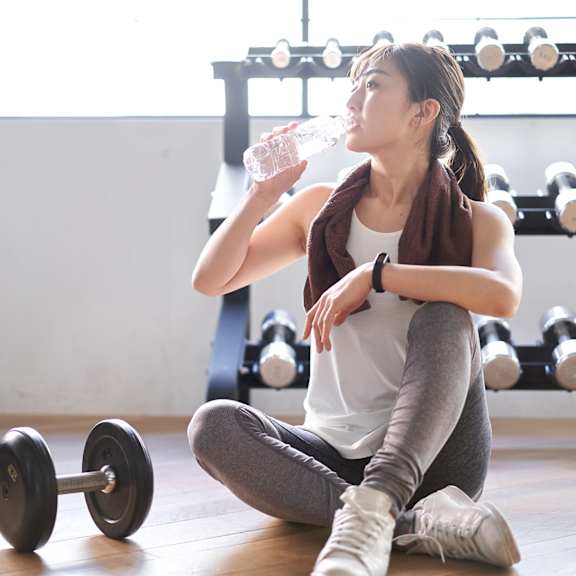a woman is sitting on the floor with a dumbbell beside her.