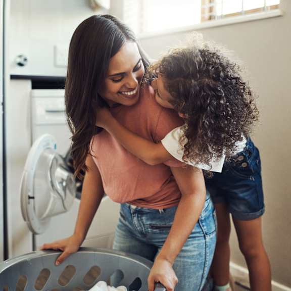 a woman and a child are standing in front of a refrigerator.