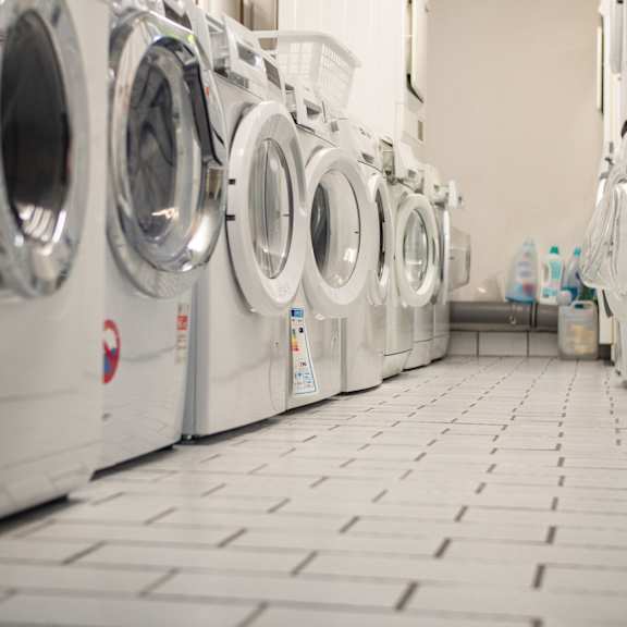 a row of white front load washing machines in a laundromat.