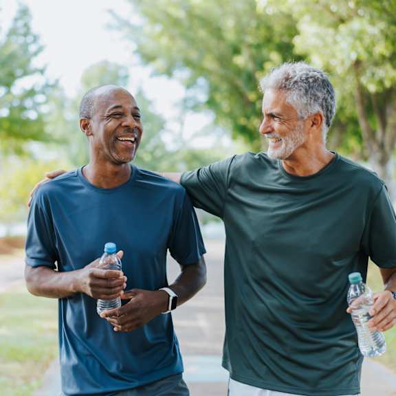 two men are walking and talking in a park.
