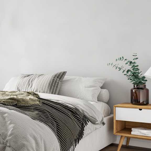 a bed with a white comforter and a green striped blanket.