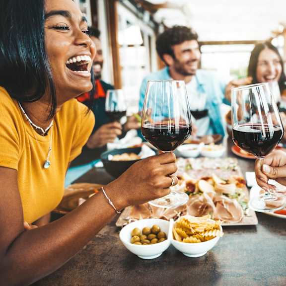 a group of people are enjoying a meal and drinks together at a table.