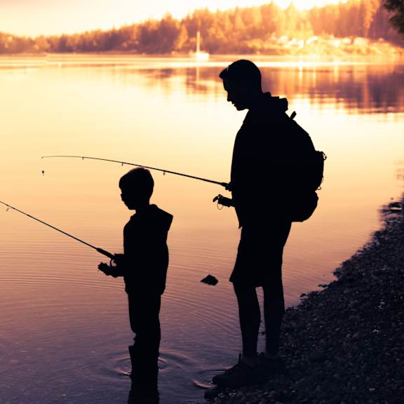 a man and a child are fishing by the water.