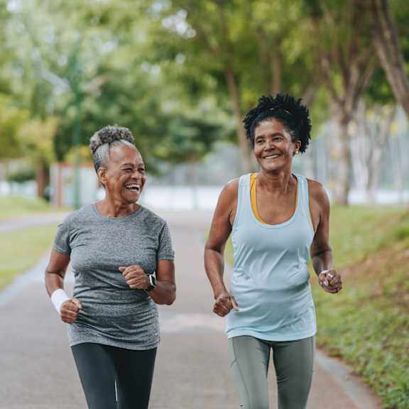 two women jogging on a path in a park.