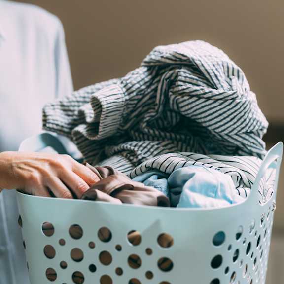 a person is holding a laundry basket full of clothes.