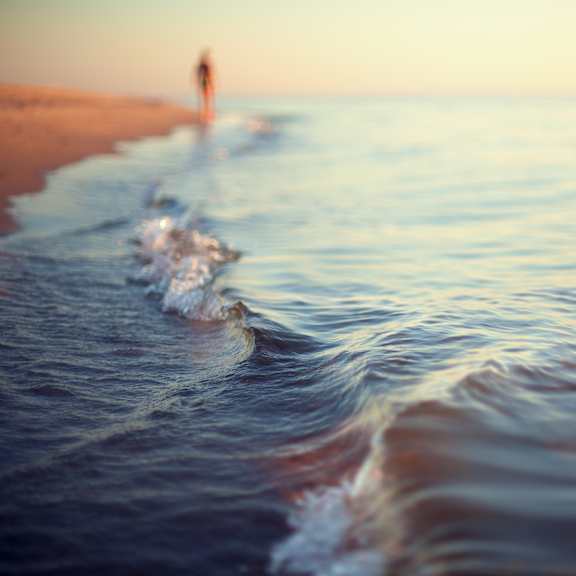 a person is walking on the beach near the water.