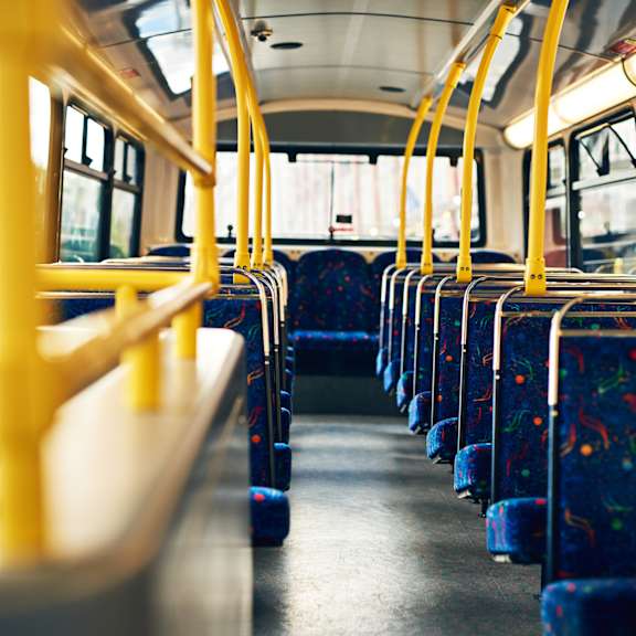 the interior of a bus with rows of seats and yellow poles.
