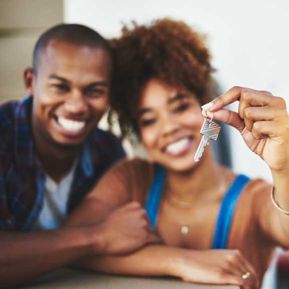 a man and woman are smiling and holding up a small object.