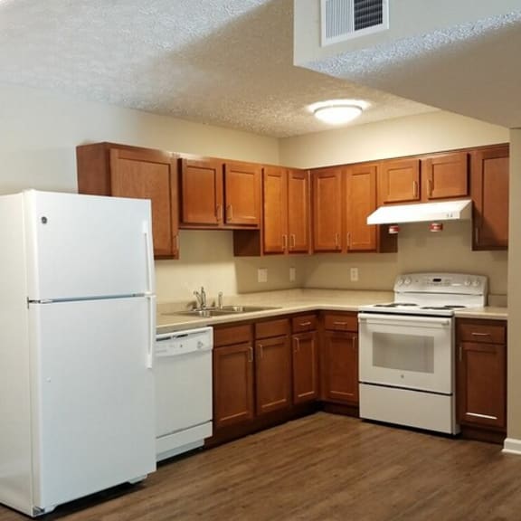 an empty kitchen with white appliances and wooden cabinets