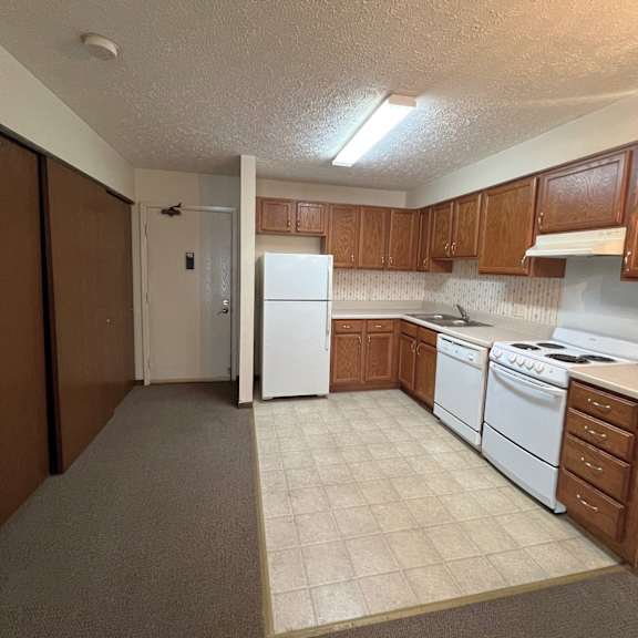 a kitchen with white appliances and brown cabinets.