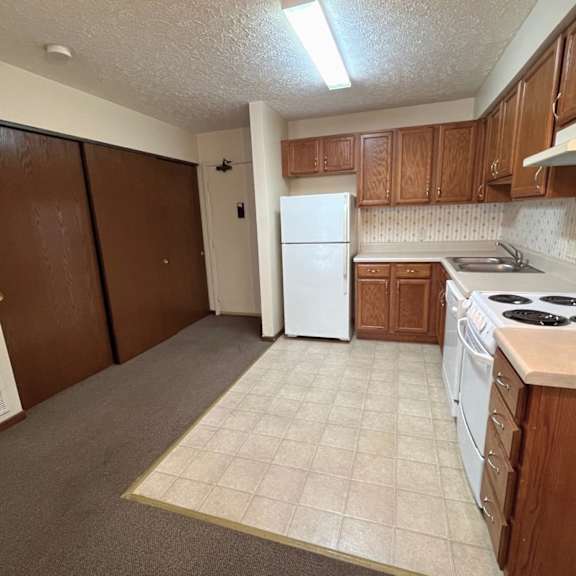 a kitchen with a white refrigerator and brown cabinets.