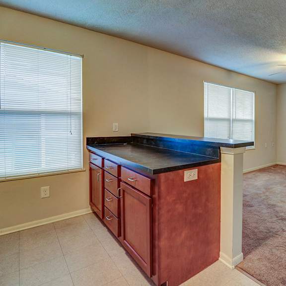 an empty living room with a counter top in the middle