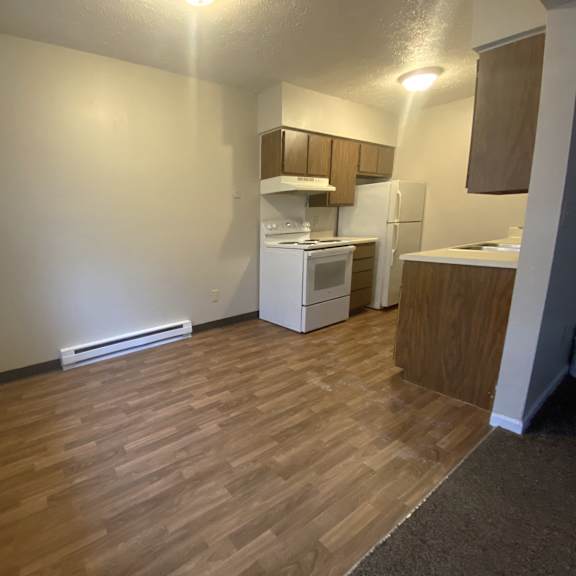 an empty room with a kitchen and a wooden floor