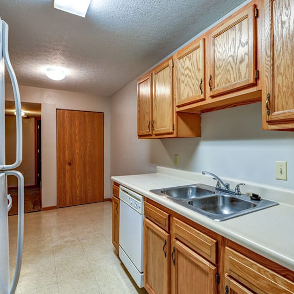 a kitchen with a sink and cabinets and a refrigerator
