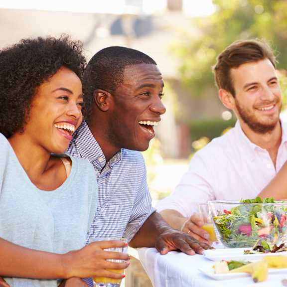 a group of people sitting at a table with food and drinks