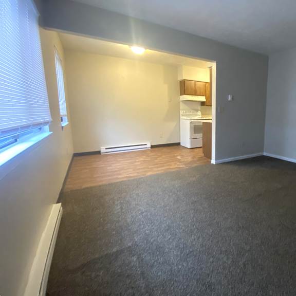 an empty living room with a large window and wood flooring