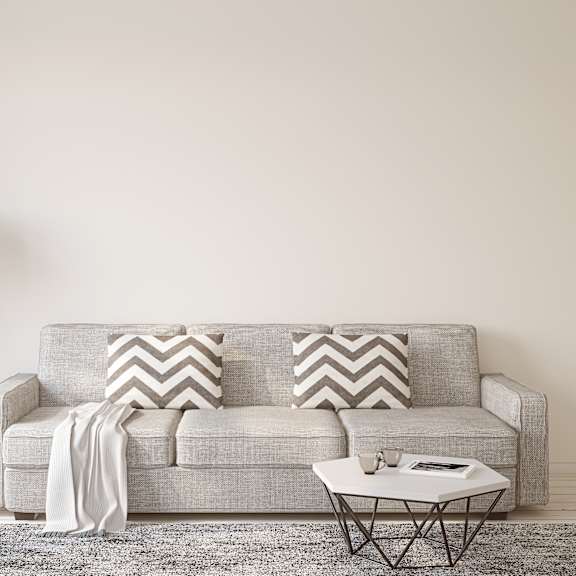 a grey couch with a white lamp and a grey and white rug in front of it.