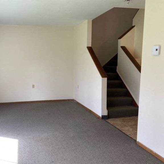 an empty living room with a staircase in the corner