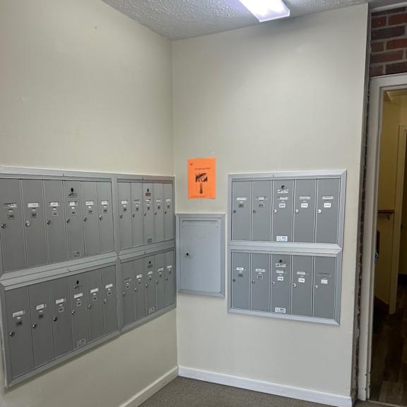 a room with a white wall and a row of grey lockers.
