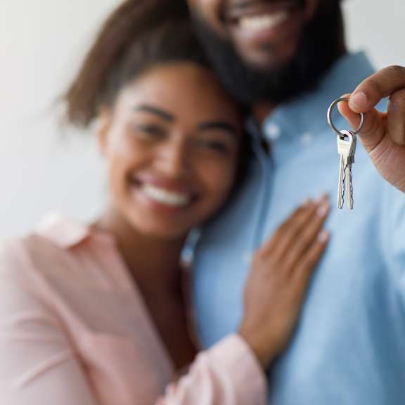 a man and woman holding a key to a house