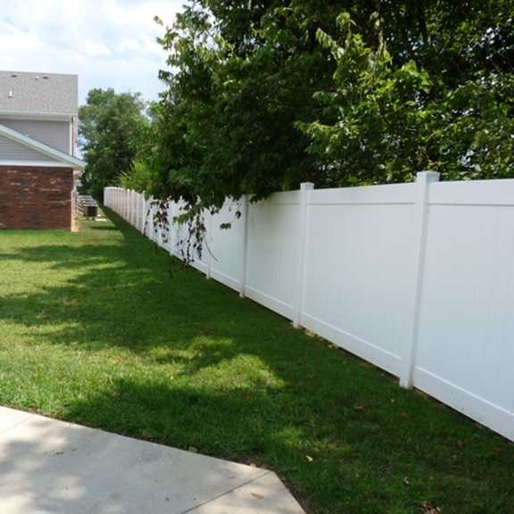 a white fence in a yard in front of a house