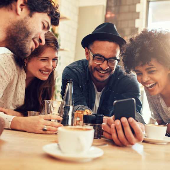 a group of people sitting at a table looking at a cell phone