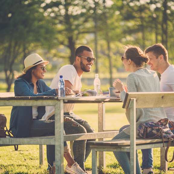 people sitting at a picnic table in a park