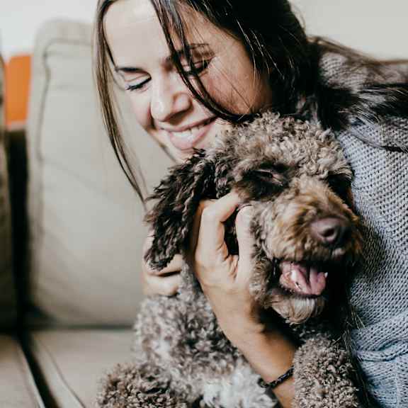 a woman holding a dog on a couch