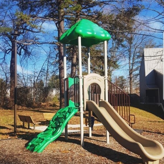a childrens playground with slides and a umbrella