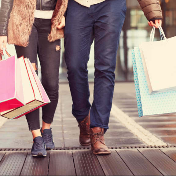 three people walking down the street with shopping bags