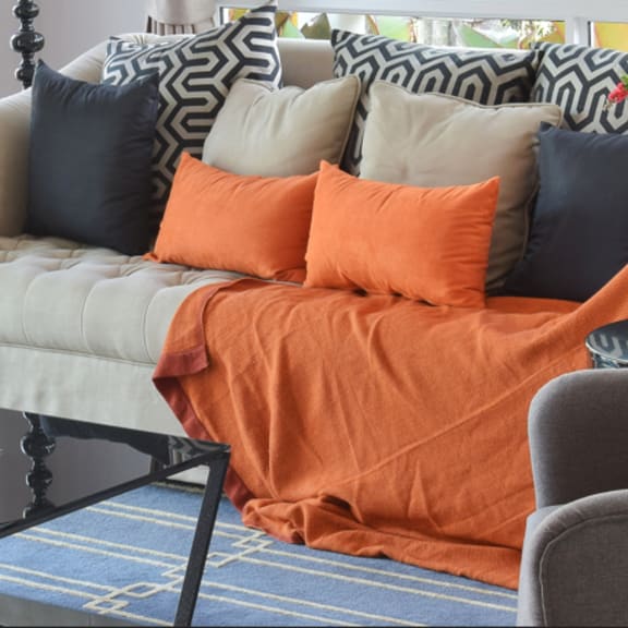 a living room with blue and orange pillows and a couch