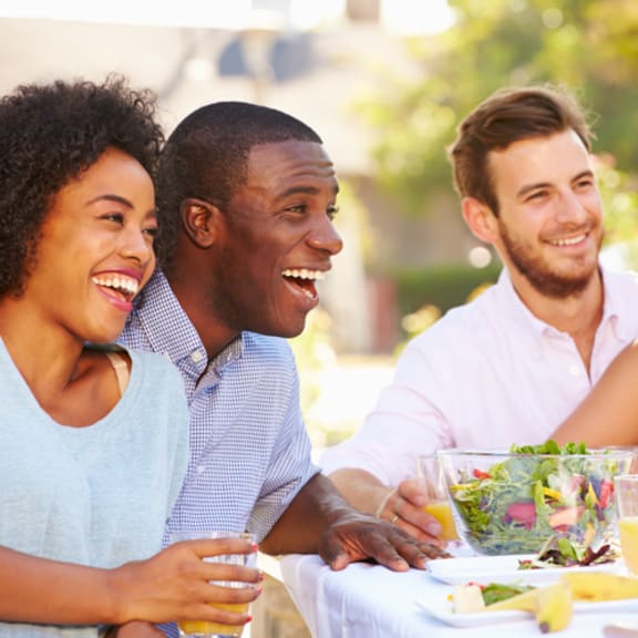 a group of people sitting at a table with food and drinks